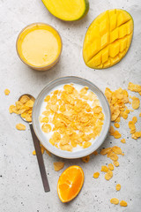 Breakfast which consist of different yellow ingredients - sereales and fruits. Gray background
