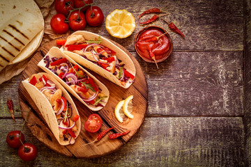 tacos  Mexican food with chicken, pepper, tomatoes, cabbage and salsa on a wooden Board