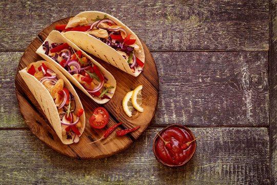 tacos  Mexican food with chicken, pepper, tomatoes, cabbage and salsa on a wooden Board