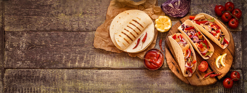 tacos  Mexican food with chicken, pepper, tomatoes, cabbage and salsa on a wooden Board
