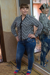 woman near the wardrobe,A woman in jeans stands near a wardrobe with a mirror