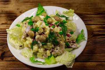 Potato salad with marinated mushrooms, eggs, red onion and mayonnaise on wooden table