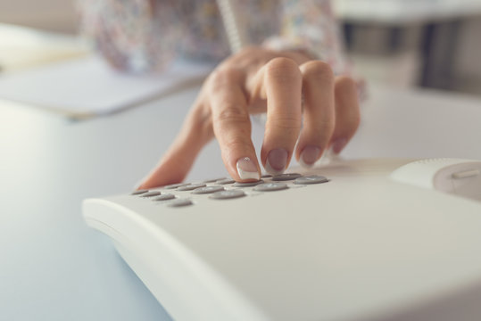 Closeup view of female receptionist dialing a telephone number