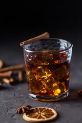 Glass of brandy or whiskey, spices and decorations on dark background. Seasonal holidays concept.