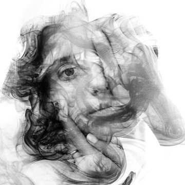 Double exposure portrait of a sensual model gently touching her face combined with a photography of smoke