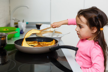 Little beautiful girl in powdery dress sits behind straw in the kitchen and looks away, close-up, indoors