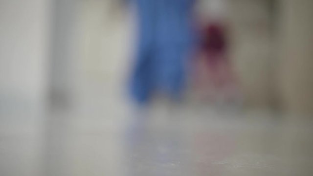 Little unrecognizable kid in the pants oversize walks away from the camera, becoming blur. Concept of childhood, growing up