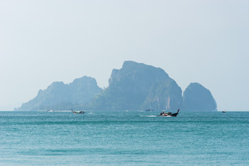 Boat sails to the sea in the turquoise waters against the rocks on the island in Asia in Thailand,...