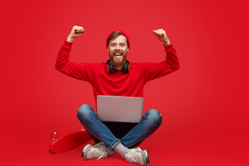 Stylish coder with laptop celebrating success - obrazy, fototapety, plakaty