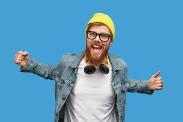 Excited trendy guy dancing and looking at camera
