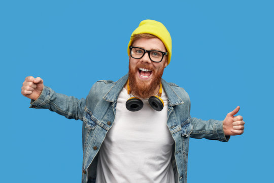 Excited trendy guy dancing and looking at camera