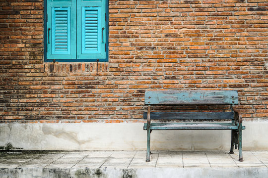 blue window, rustic bench chair by brick wall exterior
