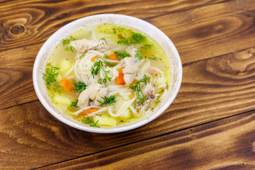 Chicken soup with noodles and vegetables on wooden table