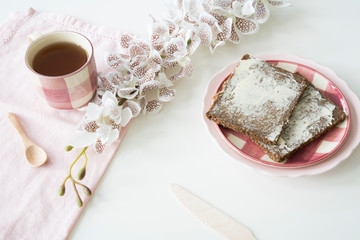 rye bread, Dutch roggebrood, on pink plate. Cup of tea, flowers and white background