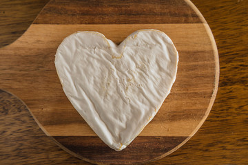Fluffy cheese heart shape on the wooden cutting board top view