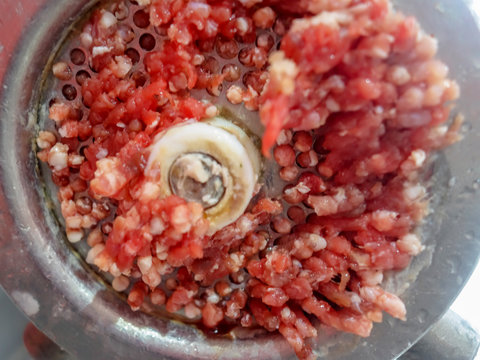 Close up front part of mincing-machine with meat in -