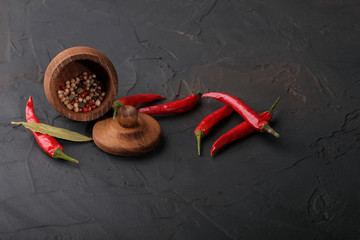 Pods of red hot pepper and pepper peas in a wooden bank on a dark background.