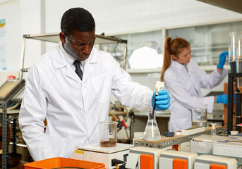 Focused man lab technician in gloves working with reagents and test tubes