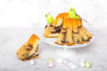 Smaczna babka wielkanocna, pisanki i odekoracyjne ptaszki na białym drewnianym tle. © czarny_bez