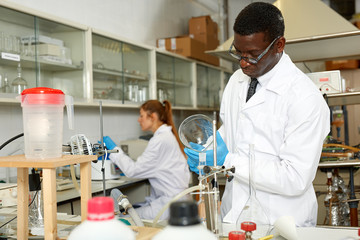 Serious man lab  scientist in glasses working with reagents and test tubes