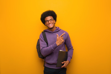 Young african american student man pointing to the side with finger