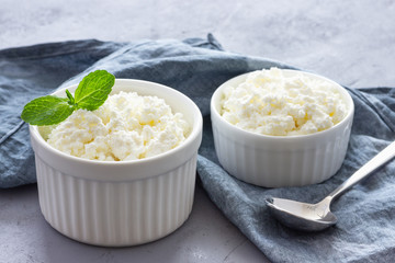 Organic cottage cheese in bowl on blue napkin. Gray background.