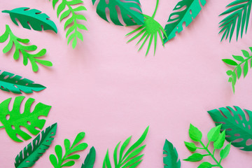 tropical leaves cut from paper on a pink background.