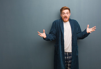 Young redhead man in pajama celebrating a victory or success