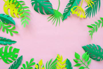 tropical leaves cut from paper on a pink background.