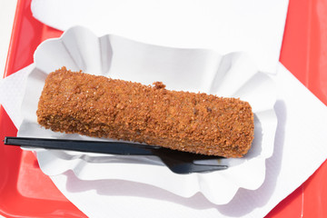 close up Dutch fried snack croquet, kroket, on white paper bowl with plastic fork