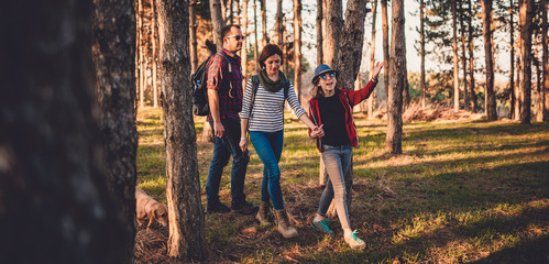 Family with dog hiking on a pine forest