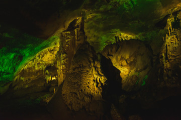 Prometheus Cave in Georgia. Multi-colored illumination of stalagmites and stalactites. Professional...
