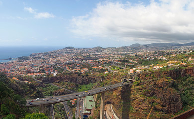 aerial panoramic view of the city of funchal with bridges and roads in front of the town and coast...