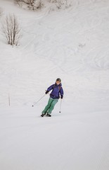 A young woman goes down on skis on the slopes of the resort Rosa Khutor, Sochi, Russia.