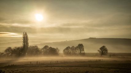 Beautiful Golden Sunrise over Foggy Field