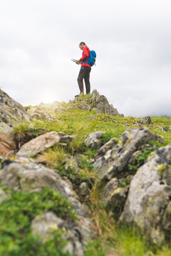 Man standing on top of a hill and checking his map in the Carpathian Mountains, Romania