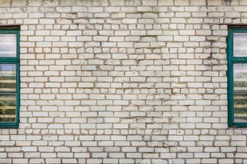 Fototapeta na wymiar Old dirty cracked white brick wall with retro wooden windows by side. Grey textured background