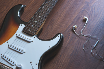 Electric guitar, headphones on the wooden background,
