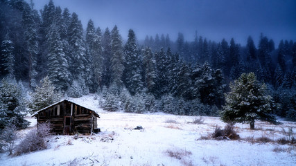 traditional old small wood cabin in the winter forest