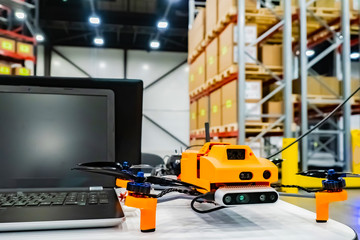 Fototapeta premium Office drone with a laptop. Warehouse equipment. Storage. Warehouse management. Drone inventory warehouse. Audit in stock. Scanning goods. Dron scans product information on the shelves.