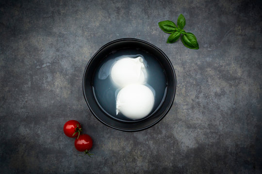 Tomatoes, basil leaves and burrata in bowl, from above