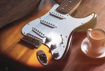Electric guitar on the wooden background, and coffee cup.