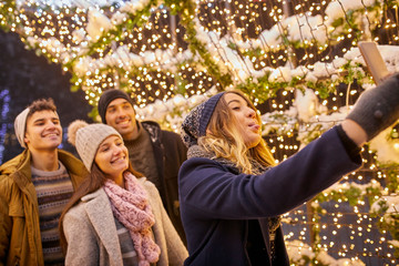 Happy friends in winter decoration taking a selfie