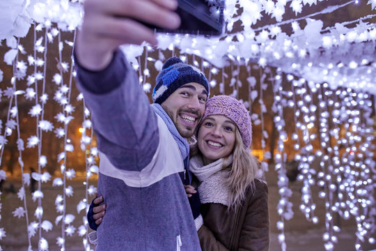 Happy young couple in winter decoration taking a selfie
