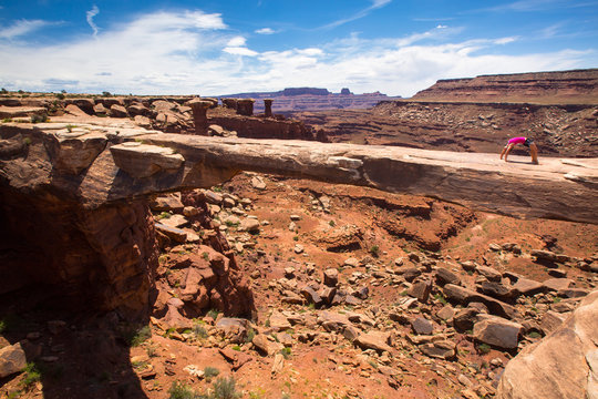 A woman does a yoga back bend on the Musselman Arch in Canyonlands National Park, Utah.