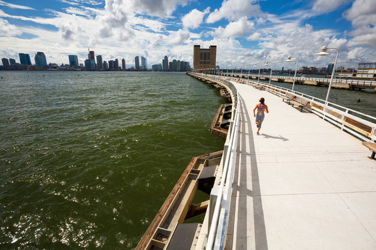 A woman runs along the Pier 34 over the Holland Tunnel near downtown Manhattan in New York City. Downtown Jersey City is in the background across the Hudson River.