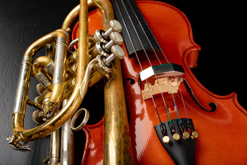 A new shining violin and an old trumpet on a dark table. Musical instruments, stringed and wind.