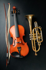 A new shining violin and an old trumpet on a dark table. Musical instruments, stringed and wind.