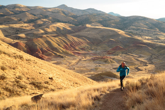 A woman trail runs along the scenic 3/4 mile Carroll Rim Trail at the Painted Hills in the John Day Fossil Beds National Monument in eastern Oregon.