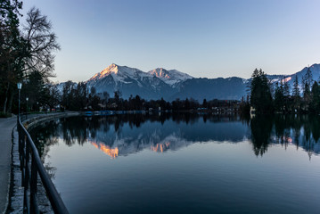 The Jungfrau and Eiger mountains reflecting the in the lake of Thun un Switzerland in the background early in the morning - 1